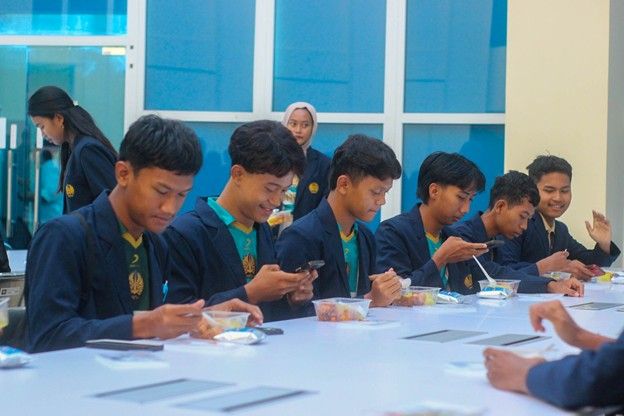 Mahasiswa Unesa Kampus 5 Magetan tampak senang dan mendokumentasikan paket sarapan bergizi yang mereka dapatkan.