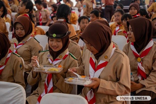 Peserta gerakan pramuka Kwarda Jatim tampak menikmati makanan bergizi gratis dalam kegiatan tersebut. Menurut mereka, selain enak, makanannya juga sehat. 