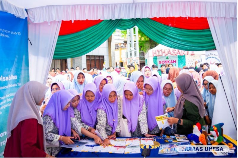 Booth Unesa dikerumuni santriwati Pesantren Tebuireng Jombang yang mengambil brosur dan menanyakan tentang informasi jalur penerimaan termasuk prodi, inovasi dan unggulan Unesa.