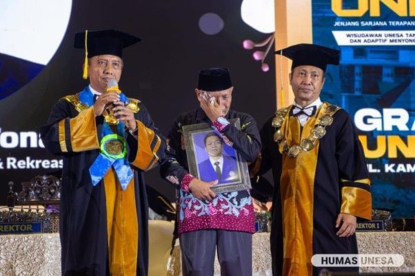 Rektor Unesa (kiri), dan dekan FIKK (kanan) mendampingi dan menguatkan Dateng Eko yang mewakili wisuda anaknya, Novandry Ari Tonang, yang berpulang ke haribaan-Nya. 