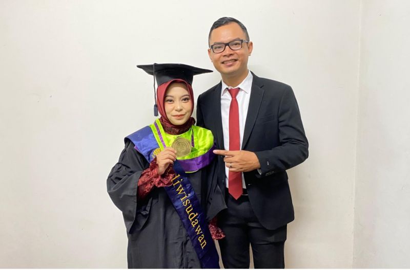 Sudah sama-sama bergelar doktor, Kartika Rinakit Adhe menjalani prosesi wisuda di GRAHA UNESA didampingi sang suami tercinta.